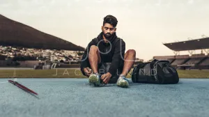 Athlete sitting on running track wearing his shoes